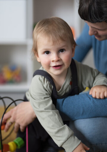 Petite fille souriante dans les bras d'une femme avec jeu éducatif crédit photo Magnific